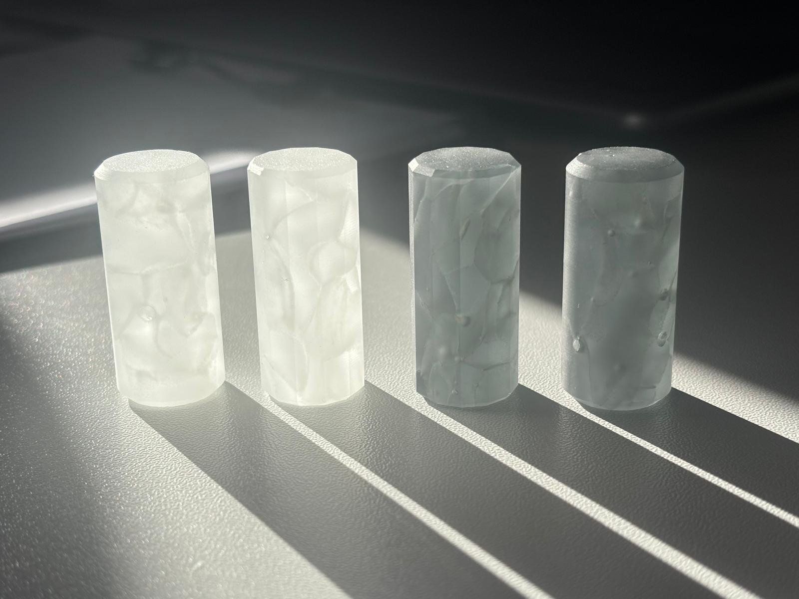 Vier bearbeitete Glaszylinder im Gegenlicht